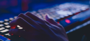 A person typing on a keyboard that is lit up against a dark background