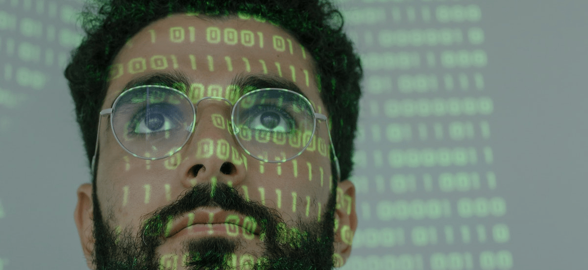 Close up of a man in glasses with reflection of binary