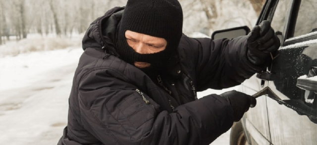 Man with a mask trying to break into a car