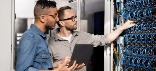 Two men with a laptop in a server room