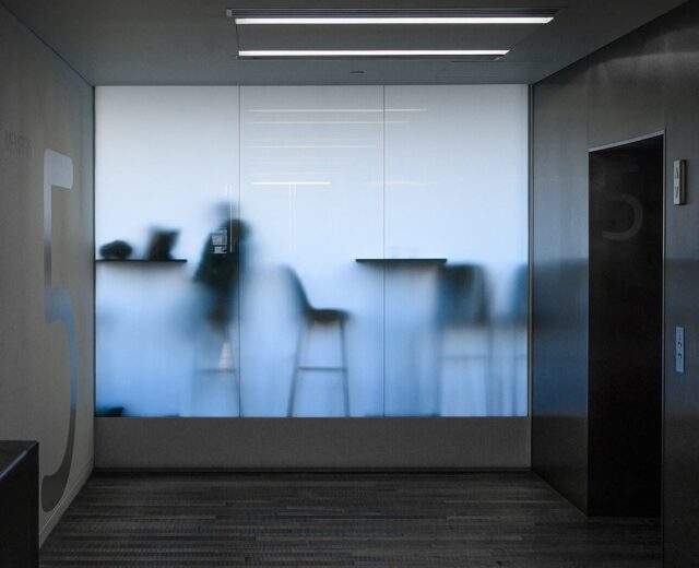 Indistinct image of a man behind the frosted glass of a panel in an office.