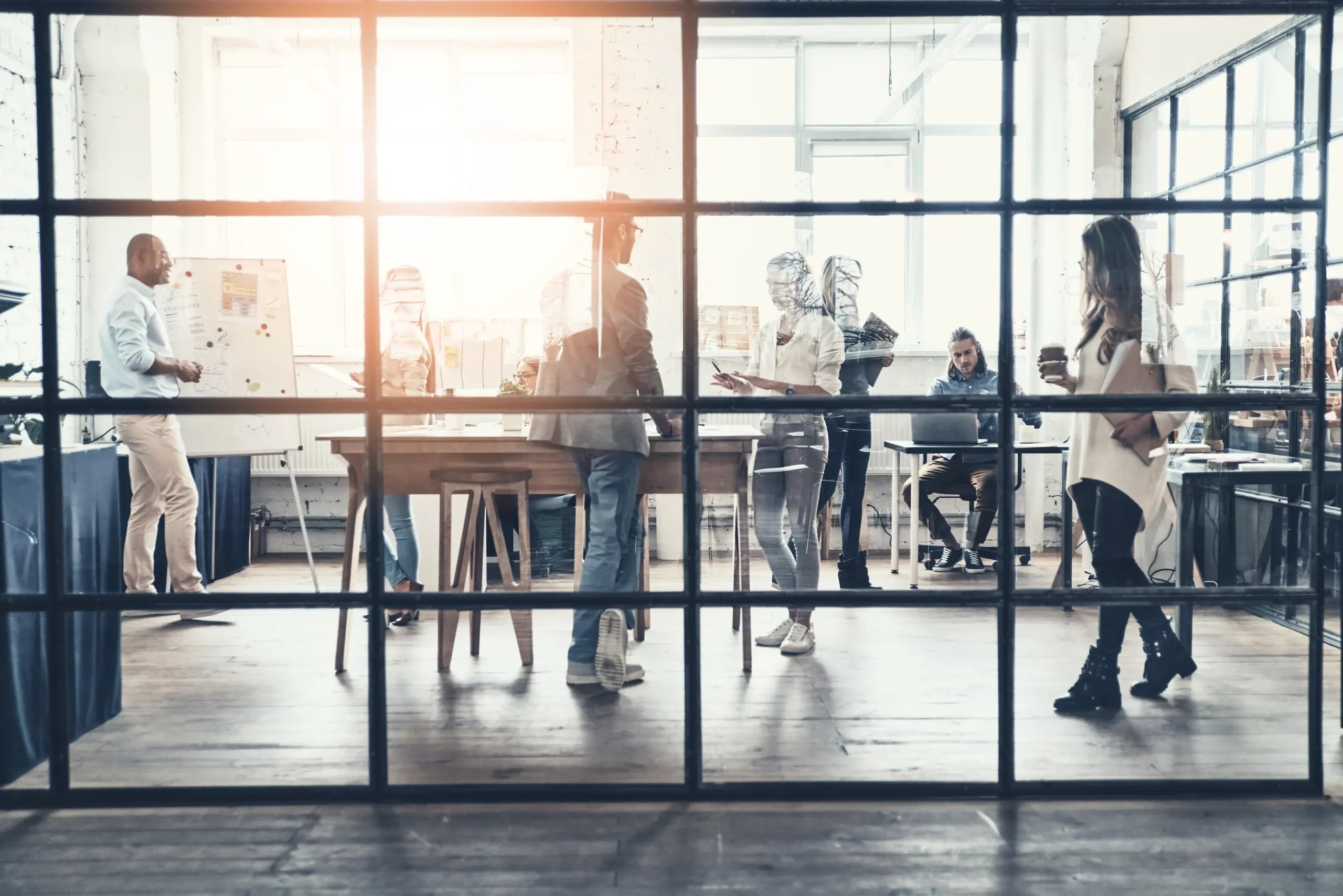 People working in a modern office setting, seen through a glass wall, creating a sense of collaboration and focus.
