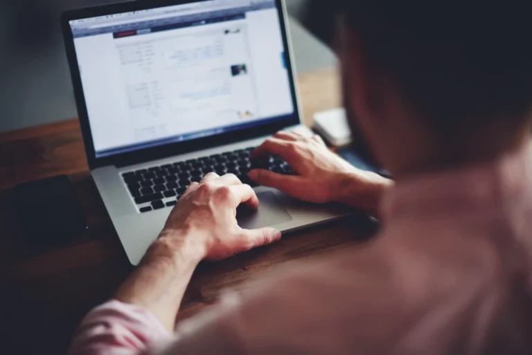 A person working on a laptop in a dark room, representing cyber threats or hacking.