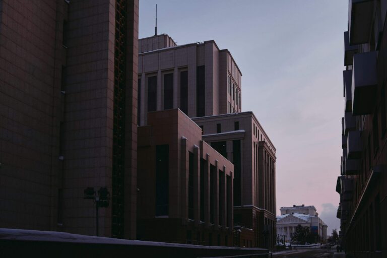 Low-angle view of institutional buildings at dusk, symbolising structure and resilience in a regulated environment
