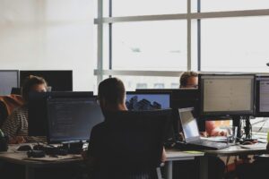 Cybersecurity team members working at computer monitors in a modern office, focusing on code and threat analysis.
