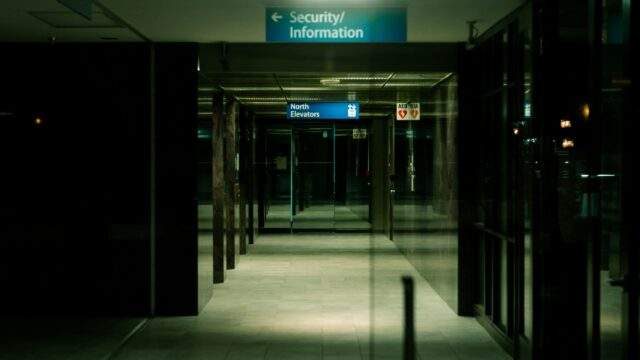 Empty office building corridor with security and elevator signs, symbolising physical security testing and intrusion risks