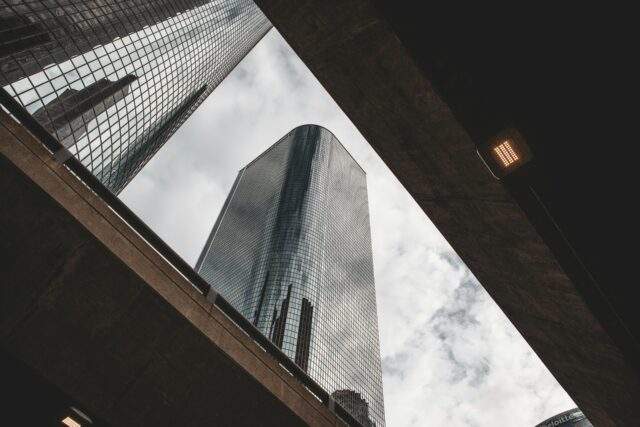 Looking up at a glass skyscraper framed between concrete overpasses, symbolising layered perspectives and security vantage points in CBEST threat intelligence