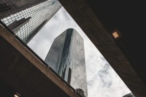 Looking up at a glass skyscraper framed between concrete overpasses, symbolising layered perspectives and security vantage points in CBEST threat intelligence