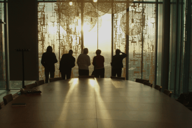 Executives in a boardroom looking out of tall windows toward the horizon, symbolising strategic vision and offensive security leadership.