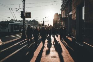 Abstract image of people walking with long shadows on a city street, symbolising human presence guiding automation in offensive security.