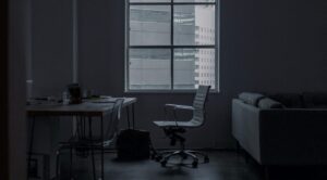 Dark office with an empty chair by a window representing constant cyber attack and unseen threats