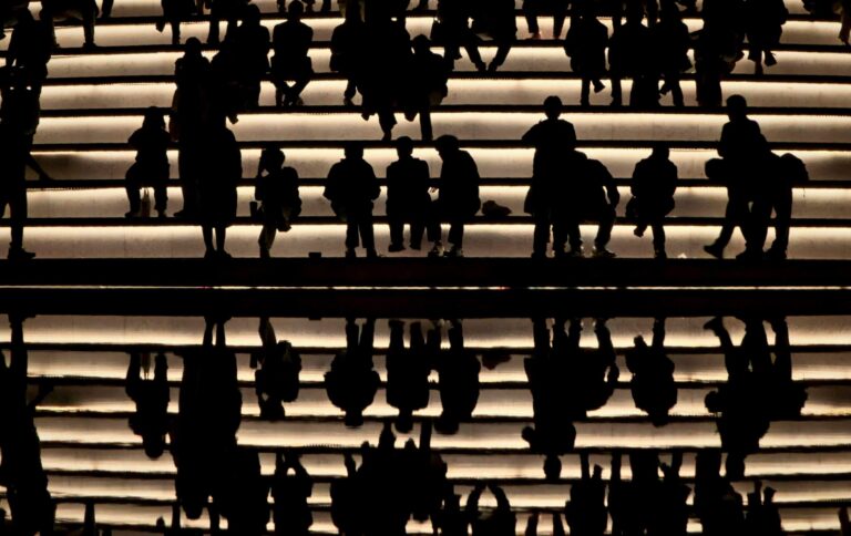 Silhouettes of a team standing together in low light, representing collaboration within a Security Operations Center.