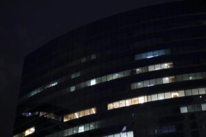 Modern office building at night showing AI agent security risks with autonomous systems running in corporate networks