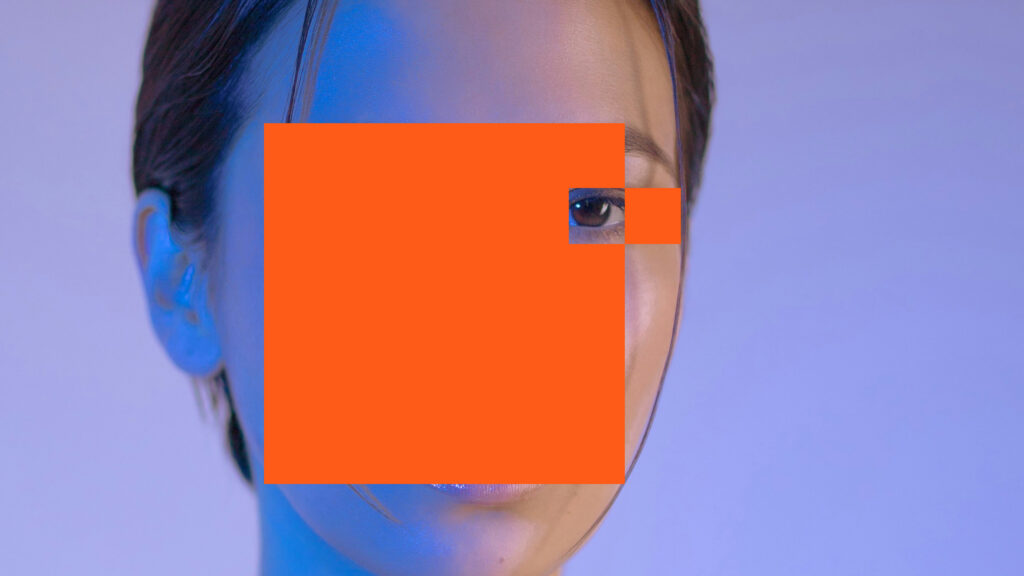 a young woman with her face covered by an orange block