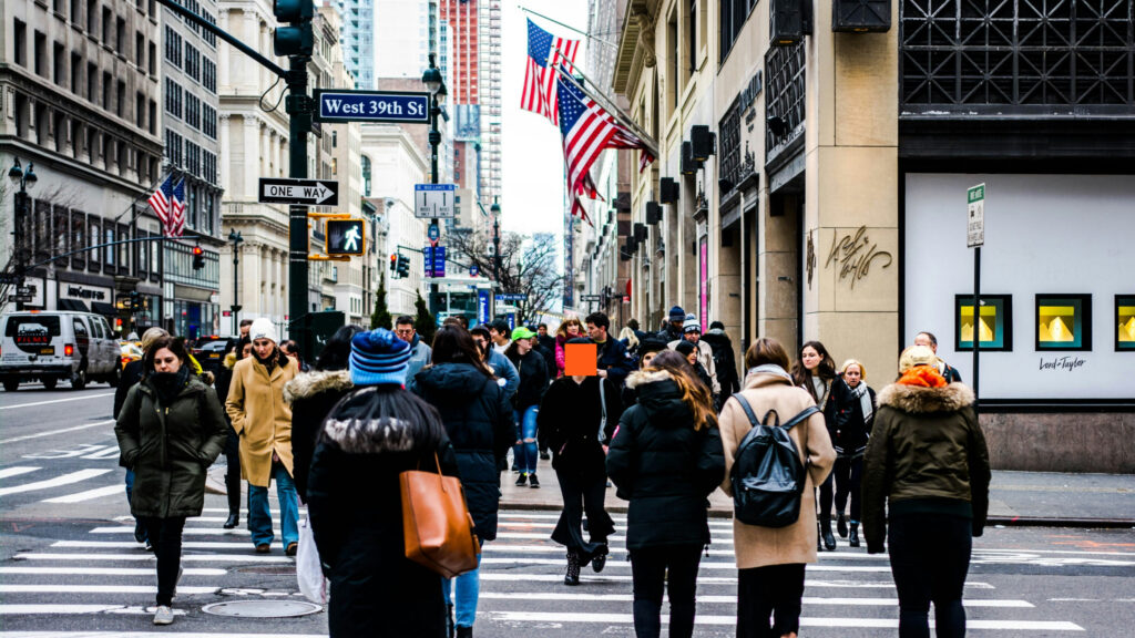 a group of people walking on a street in new york city.