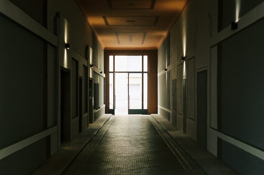 A wide empty corridor at golden hour, a door at the far end slightly open
