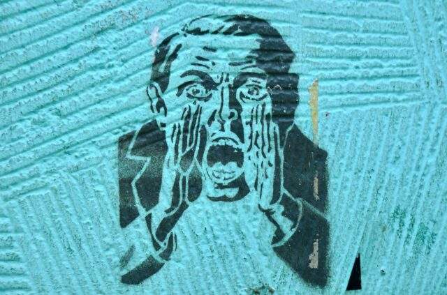 Alt text "Stencil street art of a man in a suit, one hand pressed to his face, mouth open mid-scream, on a teal wall — symbolizing loss of control and panic in the face of a security breach.