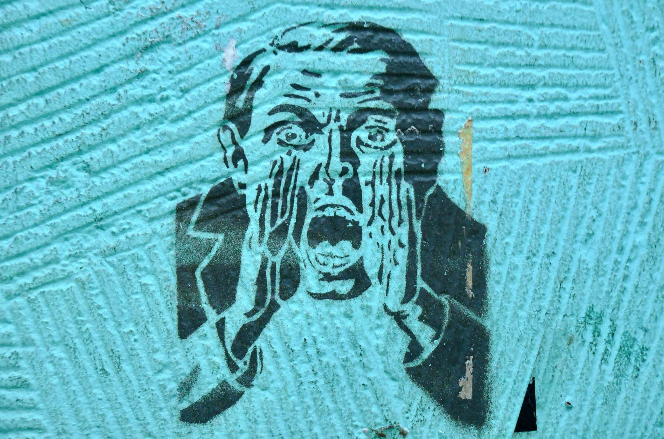 Alt text "Stencil street art of a man in a suit, one hand pressed to his face, mouth open mid-scream, on a teal wall — symbolizing loss of control and panic in the face of a security breach.
