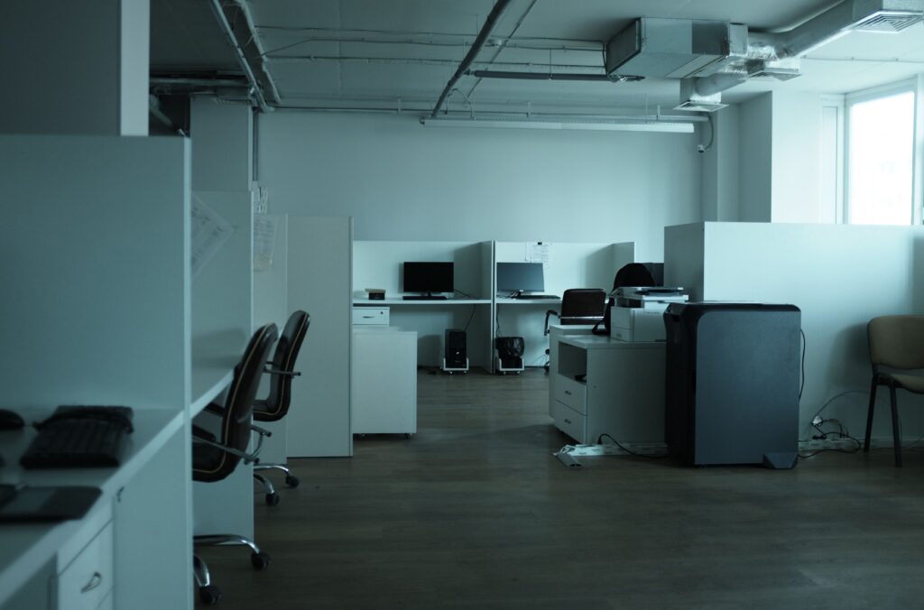 Rows of empty, identical office cubicles with monitors switched off, evoking the predictable onboarding credentials a fintech password cracking case study exploited