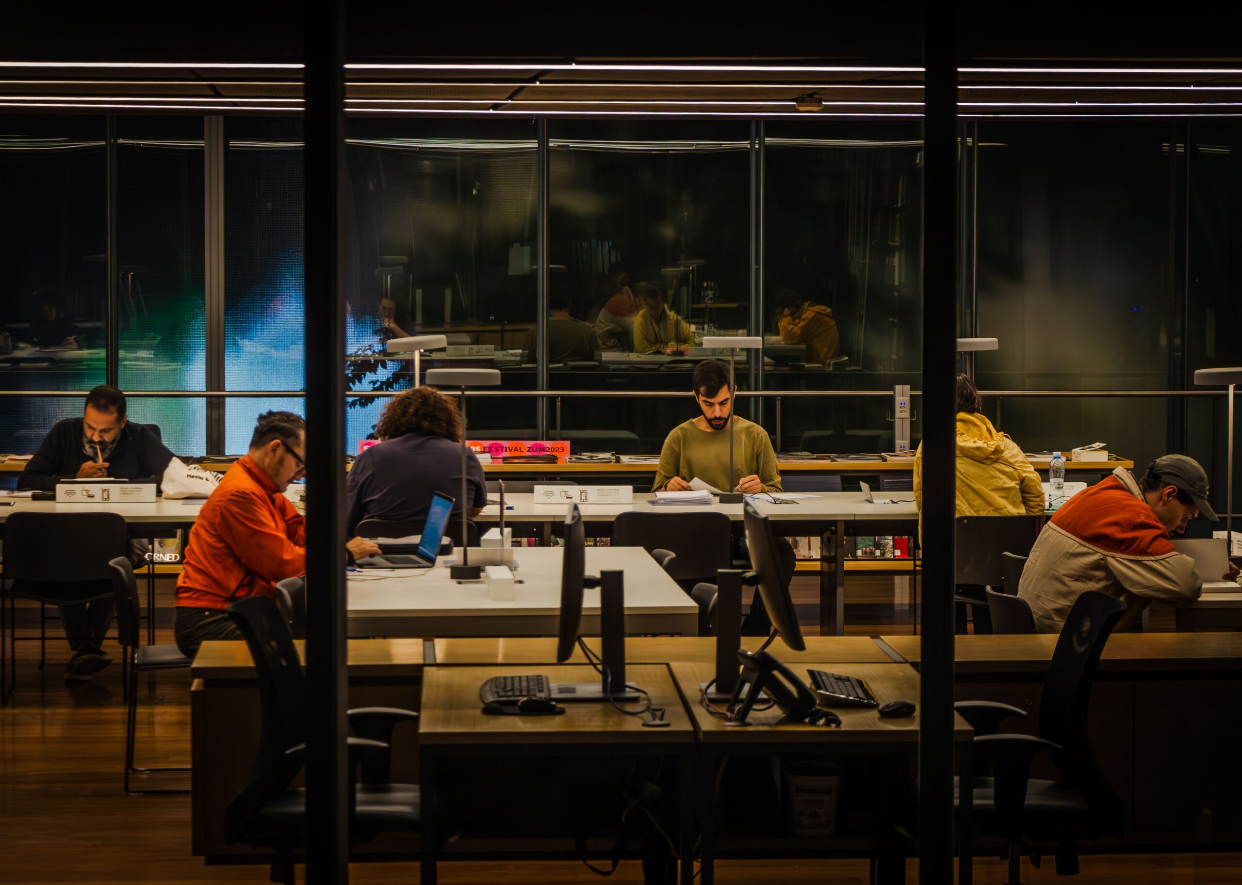 Rows of people absorbed in their own work at night, evoking the phishing simulation that slipped past a busy new hire during onboarding.