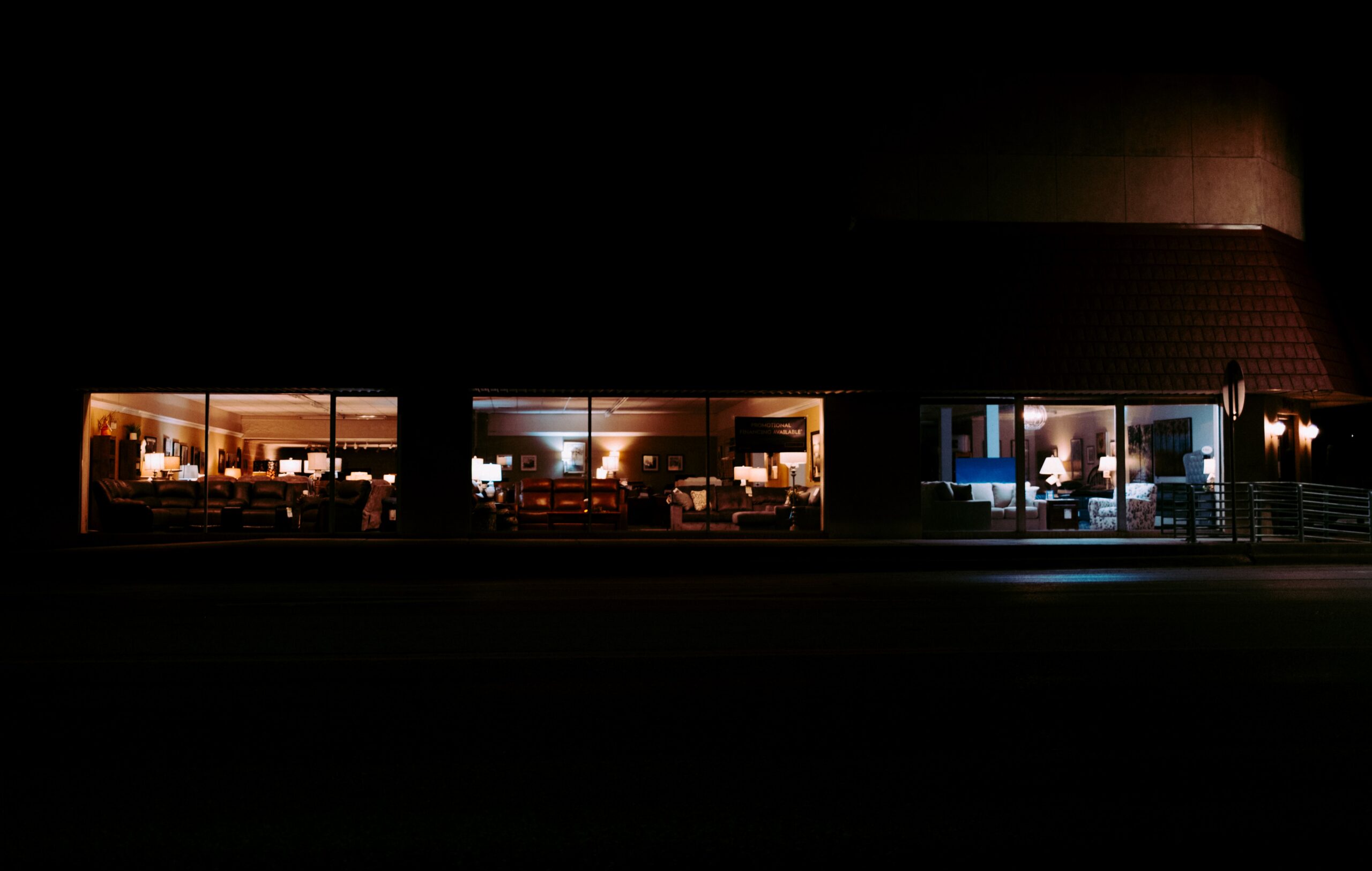 A furniture showroom lit up at night behind glass, empty and unattended, evoking a demo environment that gets none of the scrutiny given to production.