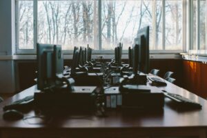 Rows of monitors seen from behind with tangled, exposed cabling, evoking the exposed API a social engineering attack used to breach a telecom provider.