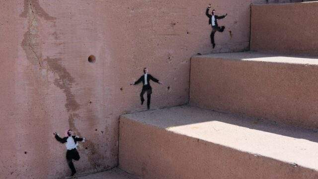 Stencilled figures scatter down a concrete stairwell, several breaking away from formation, symbolising AI agents moving outside their intended scope.