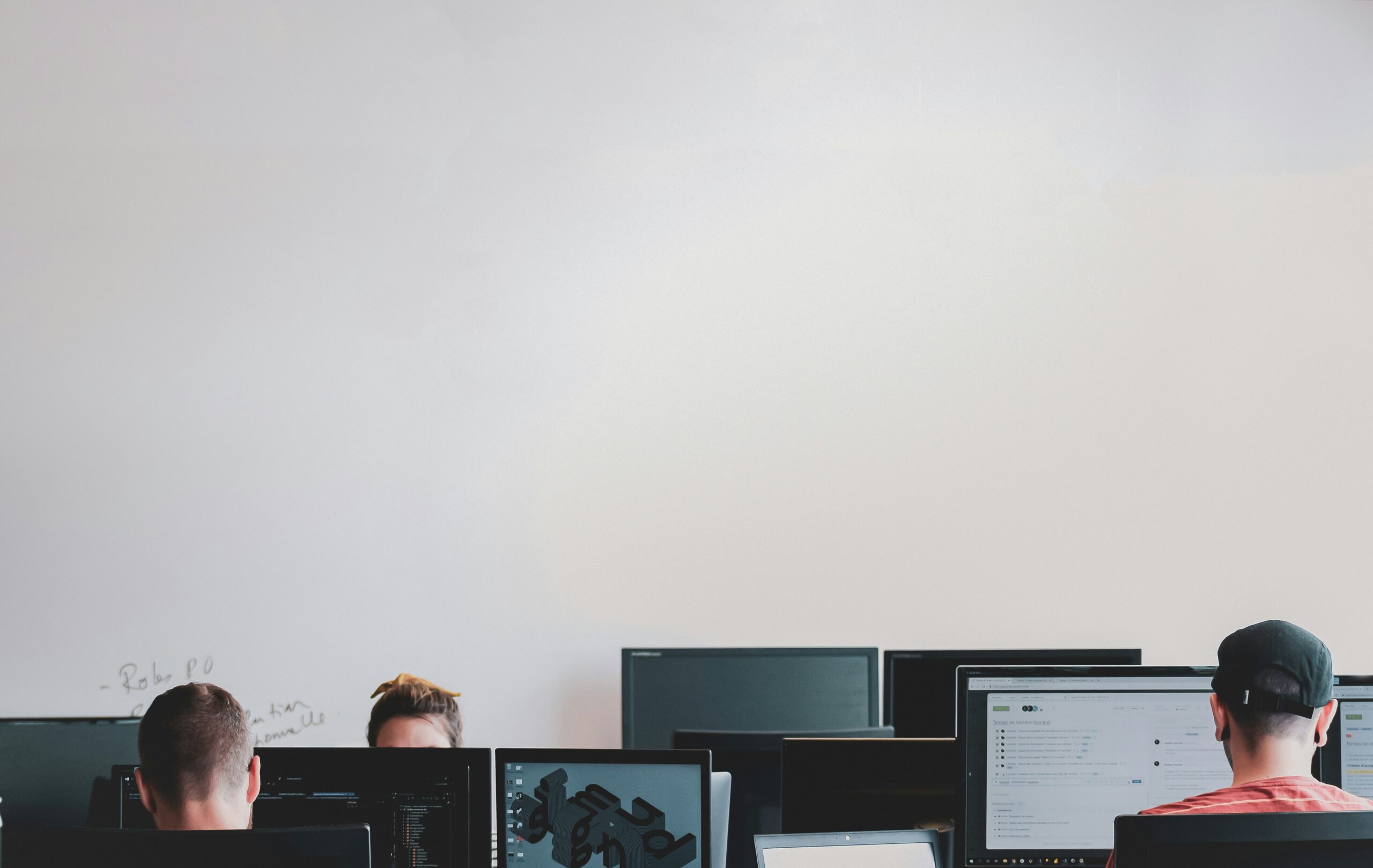 Employees working at their monitors, heads down, unaware their help desk is fielding a vishing attack disguised as a routine password reset.
