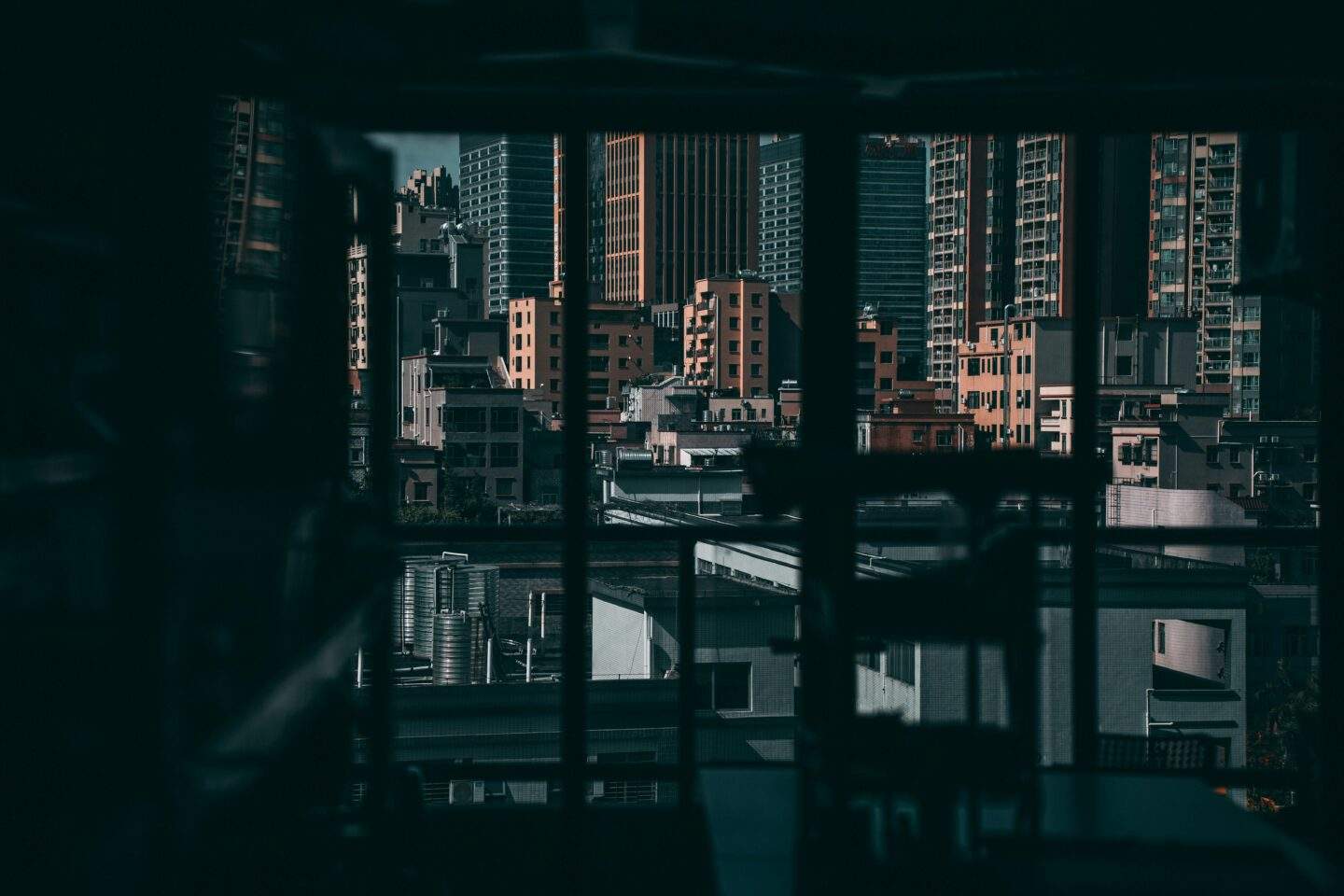 Darkened window looking out over a dense city skyline, evoking the hidden vantage point of nation-state threat actors watching unseen