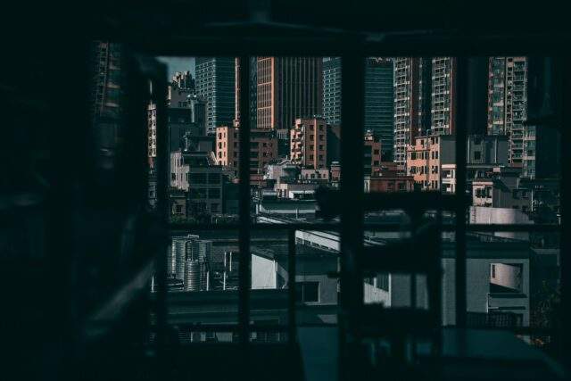 Darkened window looking out over a dense city skyline, evoking the hidden vantage point of nation-state threat actors watching unseen