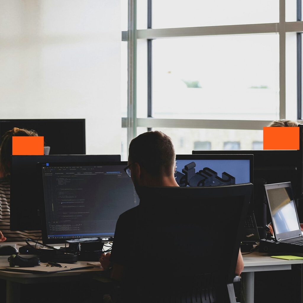Developer working at a desk with multiple monitors in an open-plan office